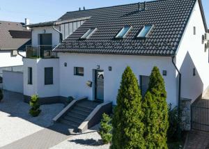 a white house with a blue door and some trees at Bala-Home Apartments & Pool in Balatonboglár