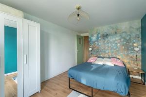 a bedroom with a blue bed with a painting on the wall at Appartement devant Nausicaa in Boulogne-sur-Mer