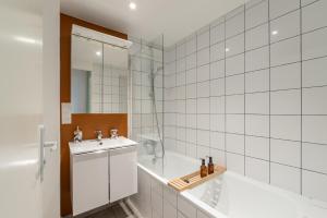 a white tiled bathroom with a sink and a shower at Appartement devant Nausicaa in Boulogne-sur-Mer +14 photos