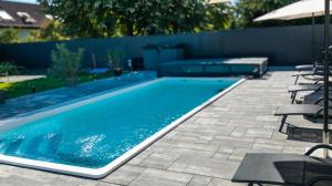 a swimming pool in a backyard with chairs and tables at Bala-Home Apartments & Pool in Balatonboglár
