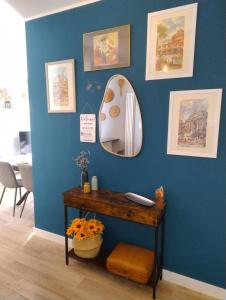 Habitación con pared azul, espejo y mesa. en Your Roman Holiday Home, en Lido di Ostia