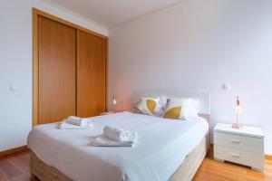 Un dormitorio con una gran cama blanca con toallas. en GuestReady - Modern space close to Formosa Beach, en Panasqueira