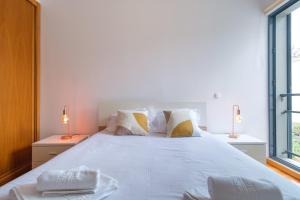 Un dormitorio con una gran cama blanca con dos lámparas. en GuestReady - Modern space close to Formosa Beach, en Panasqueira