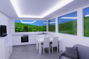 a white kitchen with a table and chairs and windows at Villa Etna in Castiglione di Sicilia