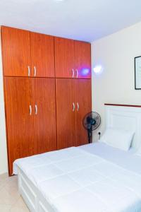 1 dormitorio con cama blanca y armarios de madera en Bright & Airy 2BR Haven, en Kampala