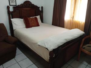 1 cama con cabecero de madera y almohadas en Casa Tranquilidad, en El Perú