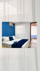 une chambre avec un lit avec un mur bleu dans l'établissement Pousada Atalaia - Arraial do Cabo, à Arraial do Cabo
