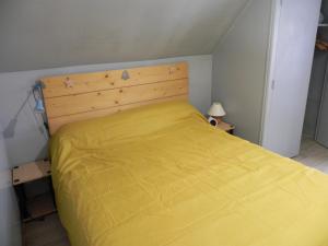 a bedroom with a yellow bed with a wooden headboard at VILLA LOZELOUX n 2 in Le Mont-Dore