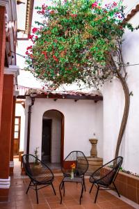 a patio with chairs and a tree with red flowers at Casa Grau in Sucre