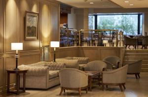 Una sala de espera con sofás, mesas y sillas. en Cyan Américas Towers Hotel, en Buenos Aires