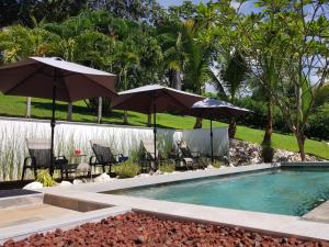 a swimming pool with two umbrellas and chairs and a pool at Baliyana Lodge in San José Pinilla +14 photos