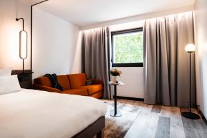 a hotel room with a bed and a couch and a window at Novotel Atria Nimes Centre in Nîmes +65 photos