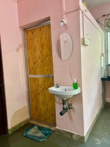a bathroom with a sink and a wooden door at Sujata Homestay 2 in Ponda