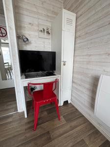 a red chair sitting in front of a desk with a television at Studio hyper centre Pornichet in Pornichet