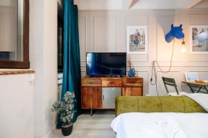 a bedroom with a tv on a wooden dresser with a green couch at Blue Camel in Old Town in Bucharest