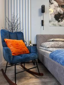 a blue chair with an orange pillow in a bedroom at Apartament Ustrzyki Dolne "Dark-Wolf" in Ustrzyki Dolne