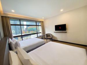 a hotel room with two beds and a window at Pinnacle Lumpinee Park Hotel in Bangkok