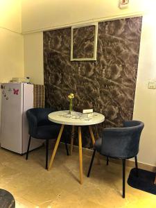 una mesa con 2 sillas y una nevera en una habitación en The Haven, en Karachi