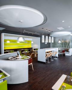 a restaurant with tables and chairs and a yellow wall at Noxi Hotel in Sétif