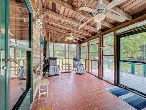 eine abgeschirmte Veranda mit einem Deckenventilator und Stühlen in der Unterkunft Cabin Retreat on 8.5 Acres at High Springs, FL in High Springs