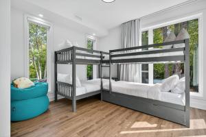 two bunk beds in a bedroom with wood floors and windows at Chalet Lumina - Private Spa, Fire Pit, Pool Table in La Conception
