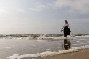 韦斯特卡佩勒Boutique Hotel Charley's的一位妇女在海滩上散步