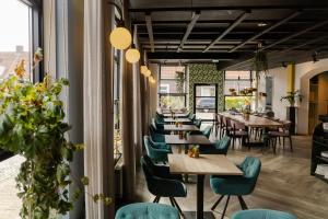 a restaurant with wooden tables and green chairs at Boutique Hotel Charley's in Westkapelle