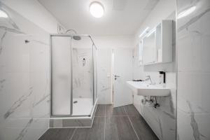 une salle de bain blanche avec une douche et un lavabo dans l'établissement The Vienna Fifteen - Boutique Hostel, à Vienne