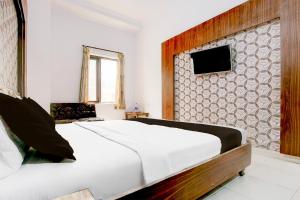 een slaapkamer met een bed en een tv aan de muur bij Hotel O Aaditya heights in Amritsar