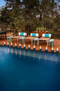 Behrai的住宿－Baghvan Pench National Park - A Taj Safari Lodge，游泳池旁的一排桌椅