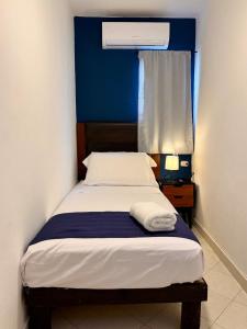 a small bedroom with a bed with a blue wall at Comodo y brillante alojamiento para 5 in Chuburná de Hidalgo +22 photos