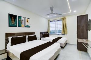 a hotel room with two beds and a window at Hotel O Vijaya Grand in Pedda Ambarpet