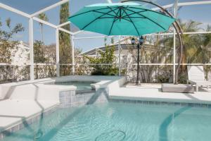 a swimming pool with a blue umbrella and a bench at Magic Retreat Orlando in Davenport