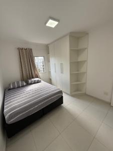 a bedroom with a bed and a window and shelves at Cobertura Hidro Spa com Espaço Gourmet Churrasqueira in Guarujá