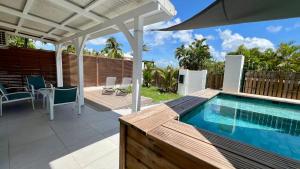 a patio with a swimming pool and an umbrella at Casa Caraïbe in Les Trois-Îlets