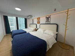 a bedroom with two beds with blue and white sheets at Spark Hotel & Serviced Apartments in Shenzhen