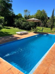 a blue swimming pool with a bench and an umbrella at Panambí Iguazú in Puerto Iguazú