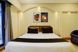 a bedroom with a large bed and a chair at Hotel O GN Motel in Mumbai