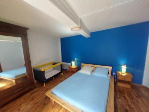 1 dormitorio con paredes azules, 1 cama y espejo en Au petit hameau Cabrespine, en Cabrespine