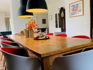 a dining room with a wooden table and red chairs at Cozy villa with wellness tub, sauna and garden in Den Ham +29 photos