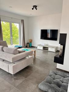a living room with two couches and a flat screen tv at Modern, new home with air cooling in Kindsbach