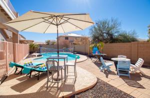 un patio con sombrilla, sillas y piscina en Casa Desert Willow 5BR Home & Heated Pool, en Casa Grande 70 fotos más