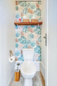 a bathroom with a toilet with a tropical wallpaper at Appart Cosy 4 Personnes - Parking Gratuit - Centre Paris 15 min Metro 4 in Bagneux