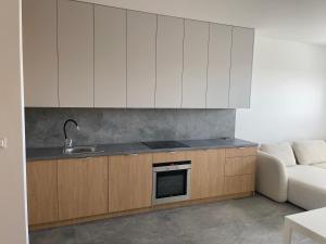 a kitchen with white cabinets and a sink and a couch at Królewska 51 in Tuszyn