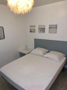 a bedroom with a white bed and a chandelier at Maisonnette Bassin d'Arcachon in La Teste-de-Buch