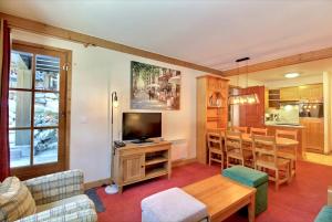 a living room with a television and a table at ARC 1950 - Appartement 6 personnes - Départ ski aux pieds - Sauna, Hammam, Jacuzzi, Piscine chauffée in Arc 1950