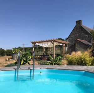 a swimming pool in front of a house with a pergola at Bienvenue chez Chris ! in Saint-Hilaire-des-Landes