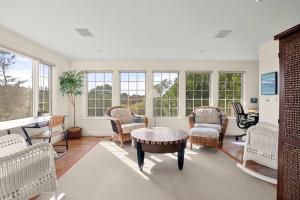 a living room with chairs and a table and windows at Water Views & Private Tennis Court in Barnstable