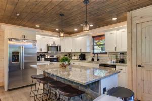 a kitchen with white cabinets and a large island with bar stools at Summit View By Avada Properties in Waldens Creek