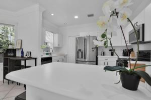 a white kitchen with a white table with a plant at Miami home -15min from Kendall Exec Airport - Pool in Hammocks